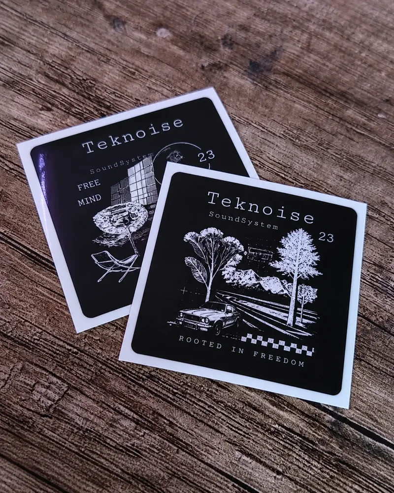 Twee zwarte vierkante stickers met witte illustraties op een houten ondergrond